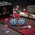 Blue flower-shaped earrings on a decorative mat with flowers and a tea cup in the background