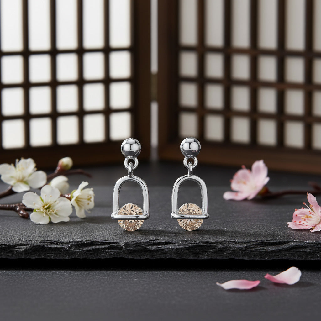 Pair of silver earrings with gold accents on a dark surface with flowers.