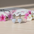 Heart-shaped earrings with floral design on a wooden surface with flowers in the background