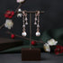 Pair of pearl earrings on a dark stand with a floral background