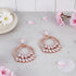 Rose gold earrings with clear stones on a light surface with flowers