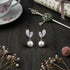 Pearl earrings on a dark wooden surface with a teacup and decorative items.