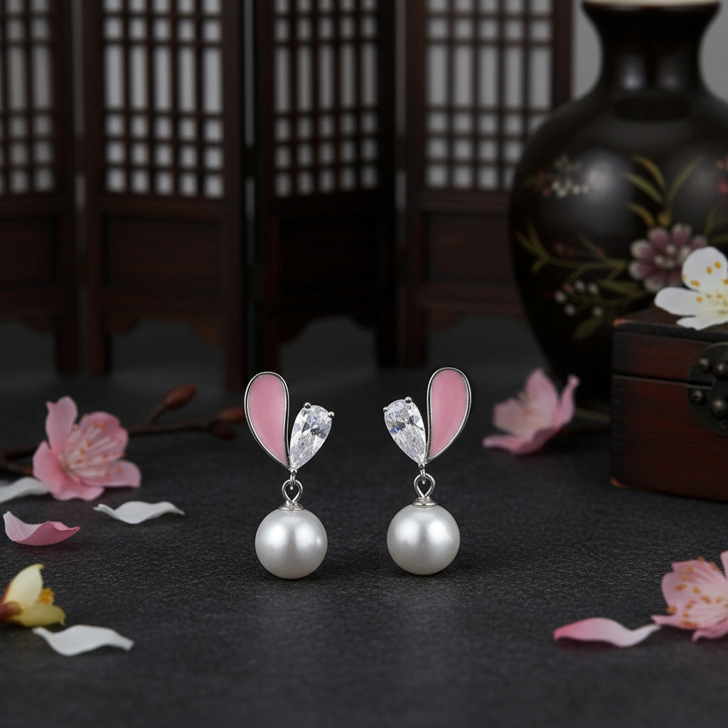 Pair of earrings with pink heart-shaped elements and pearl drops on a dark surface with floral decorations.
