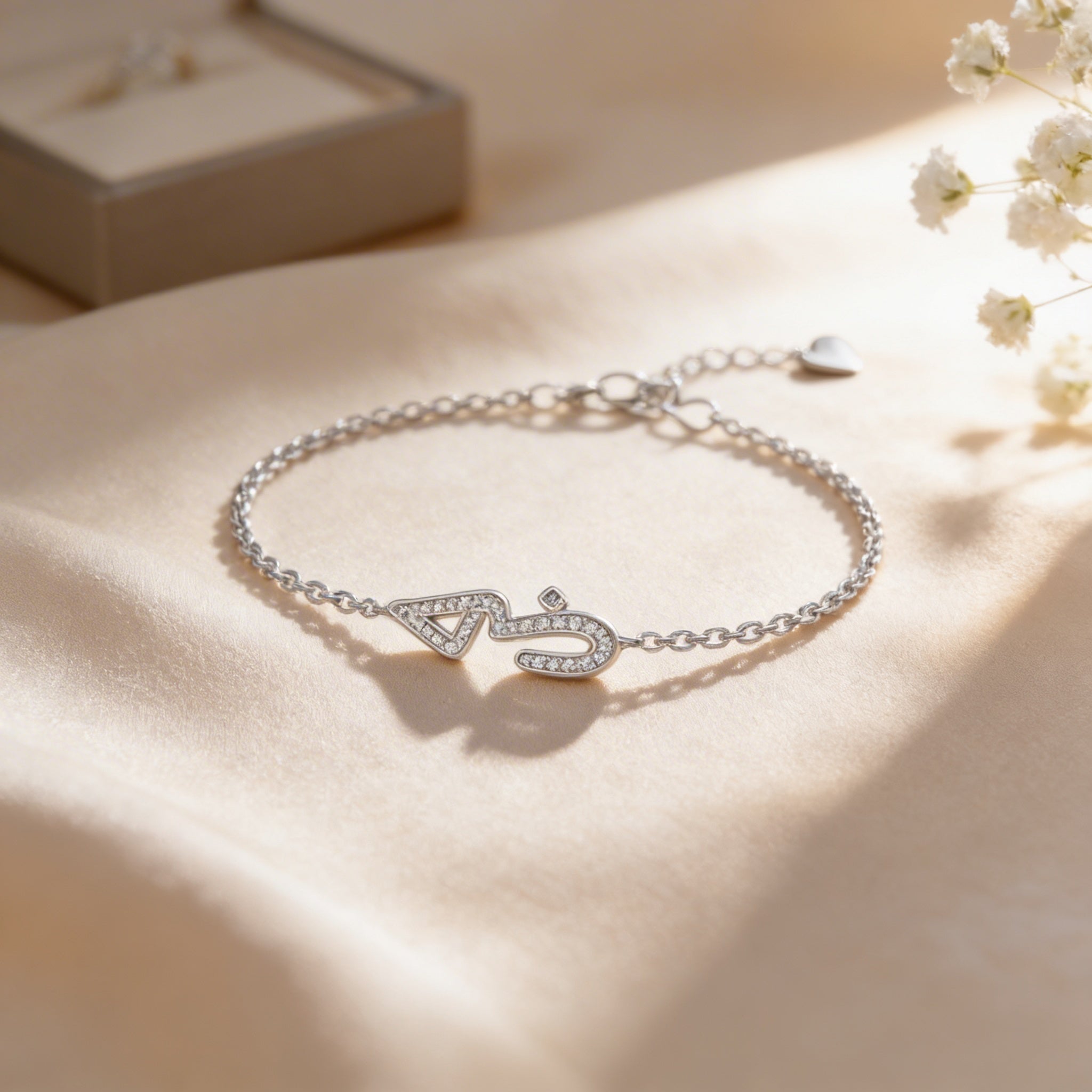 Silver bracelet with a decorative clasp on a soft beige surface with flowers.