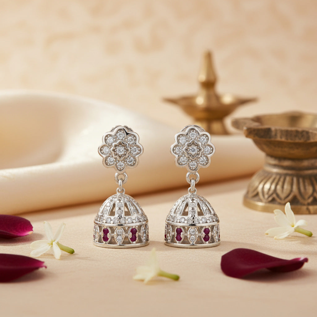 Silver earrings with floral design on a decorative background with flowers and petals.