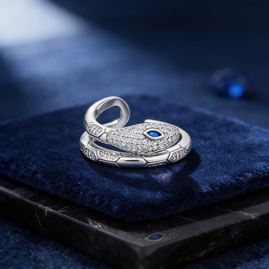 Silver snake-shaped ring with a blue gemstone on a dark blue surface