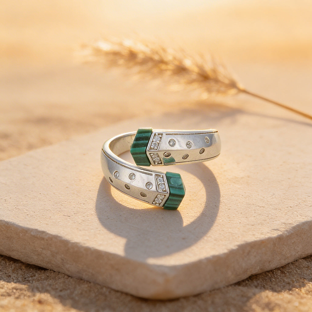 Silver ring with green accents on a stone surface with a natural background