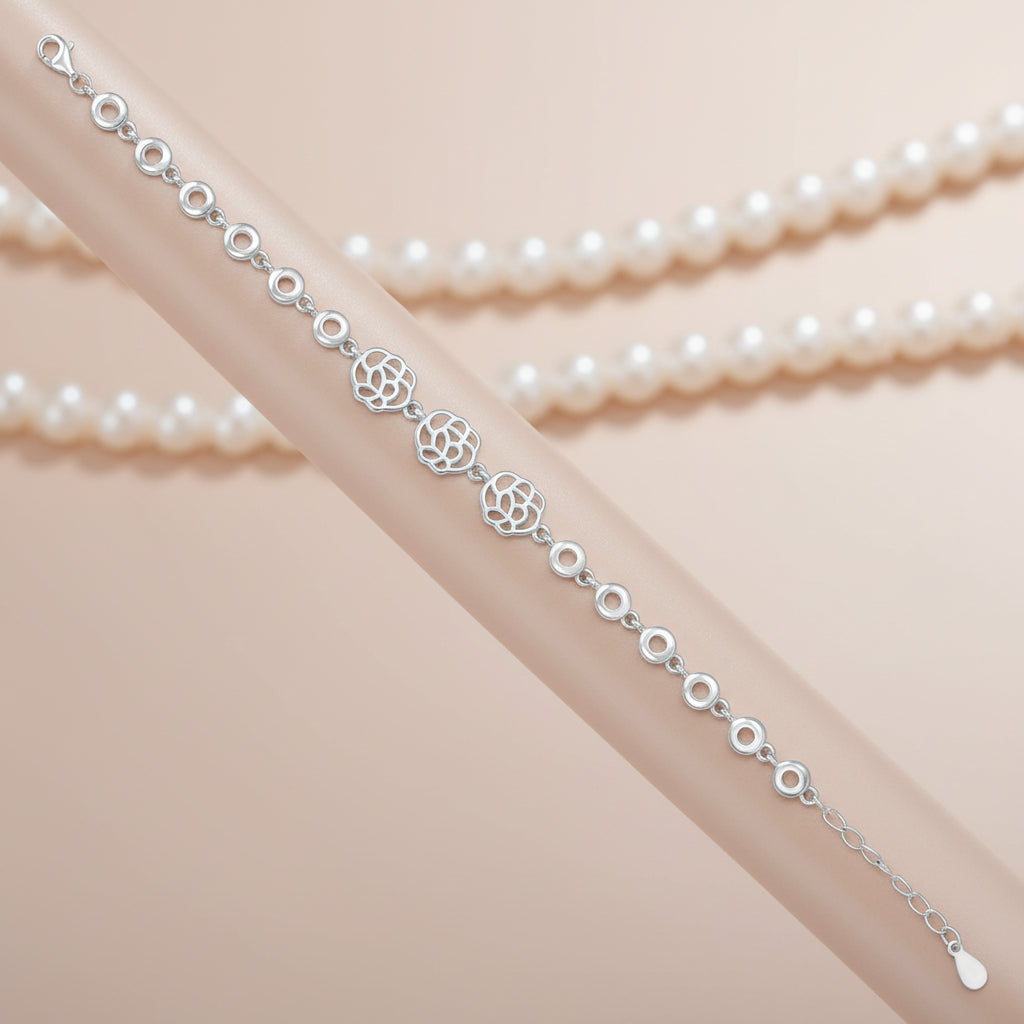 Silver bracelet with floral designs on a beige fabric background