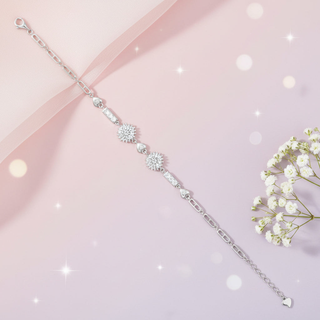 Silver bracelet with floral designs on a pink background with flowers