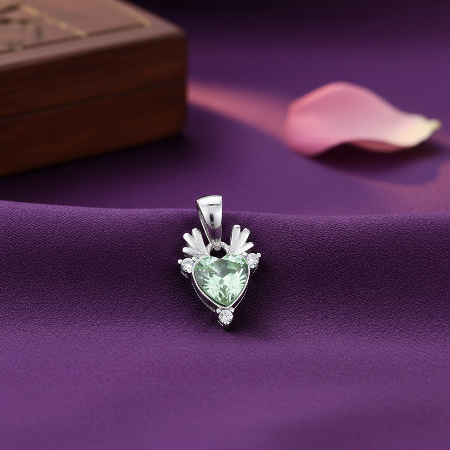 Heart-shaped green gemstone pendant on a purple fabric background