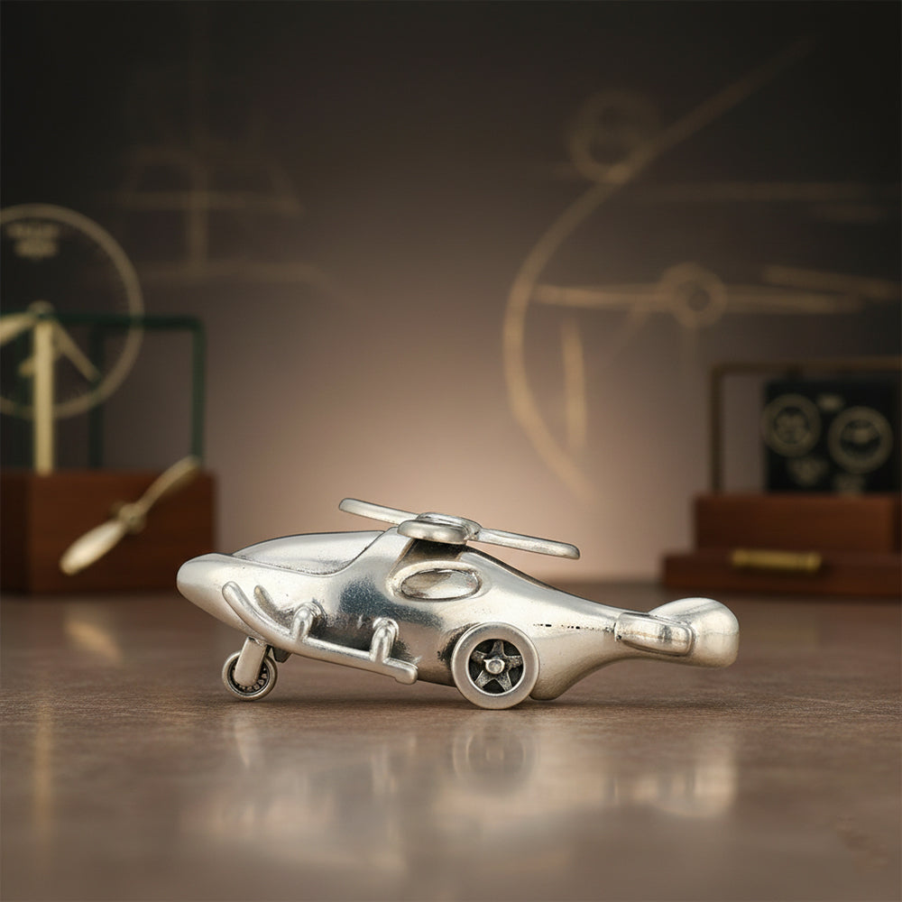 Metallic toy helicopter on a reflective surface with a blurred background