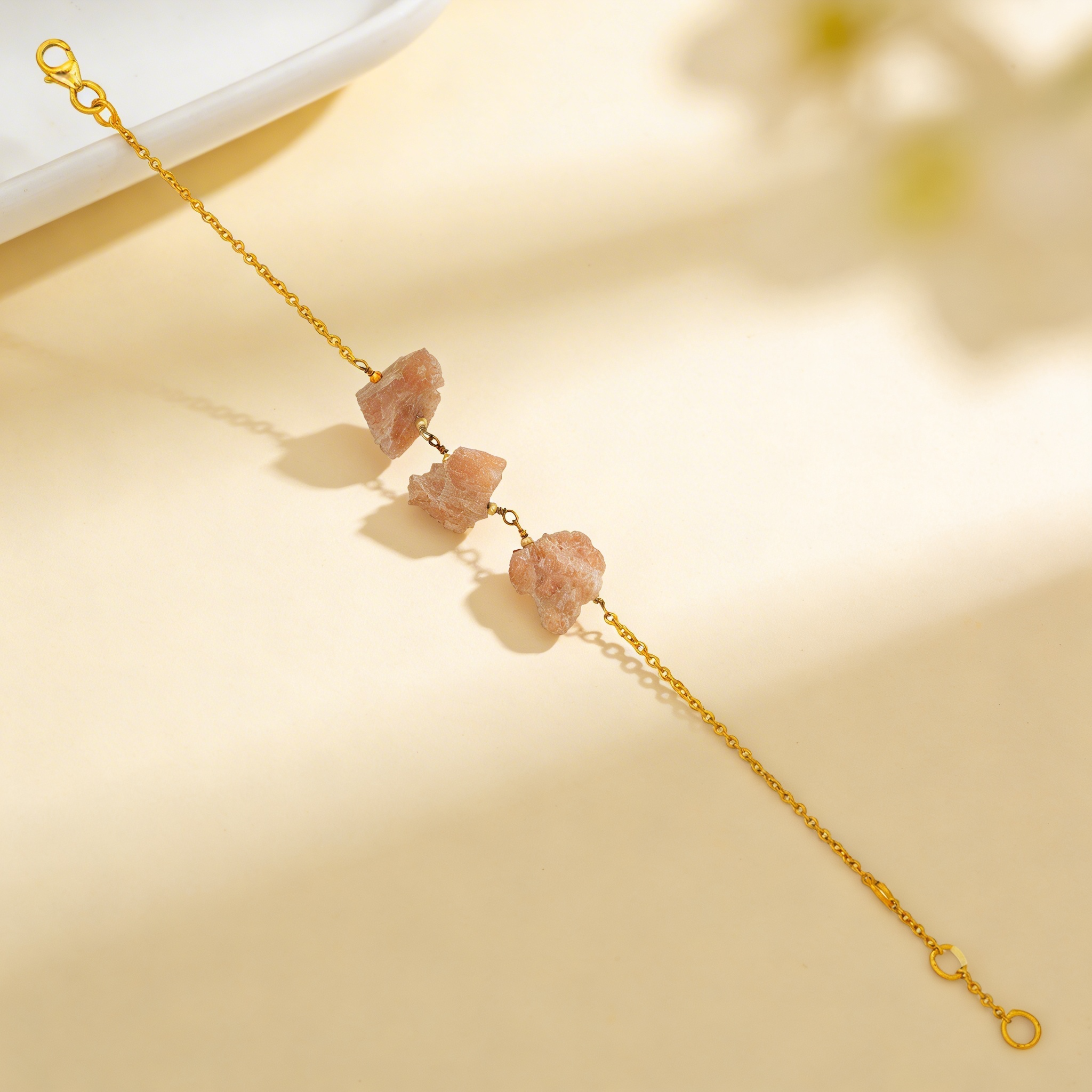 Gold bracelet with natural stone beads on a beige background