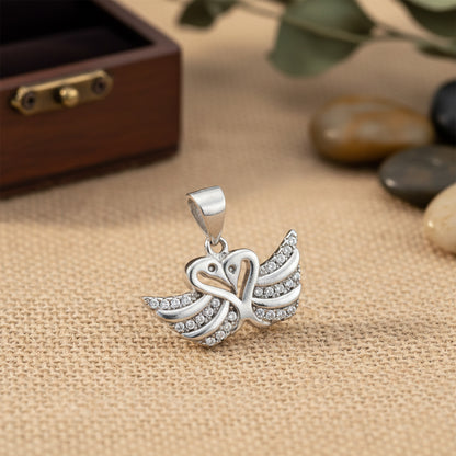 Silver butterfly pendant on a textured fabric background with stones and a wooden box.