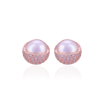 Pair of pearl earrings with rose gold and clear gemstone accents on a white background