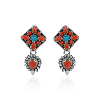 Pair of earrings with floral design featuring red and blue stones on a white background