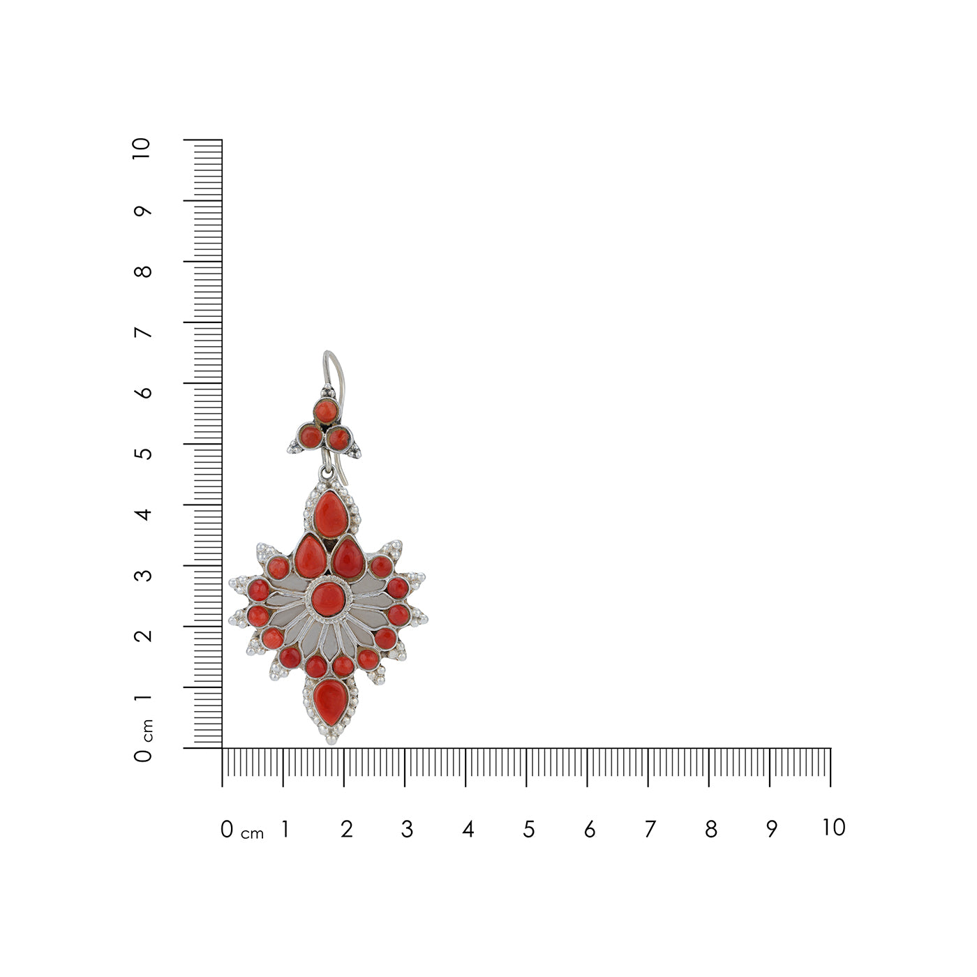 Silver pendant with red stones next to a ruler on a white background