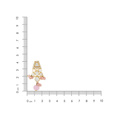 Jewelry charm with pink stones and gold accents next to a ruler for scale on a white background
