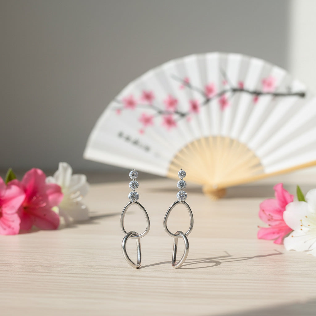 Silver earrings with floral and fan decor on a light surface