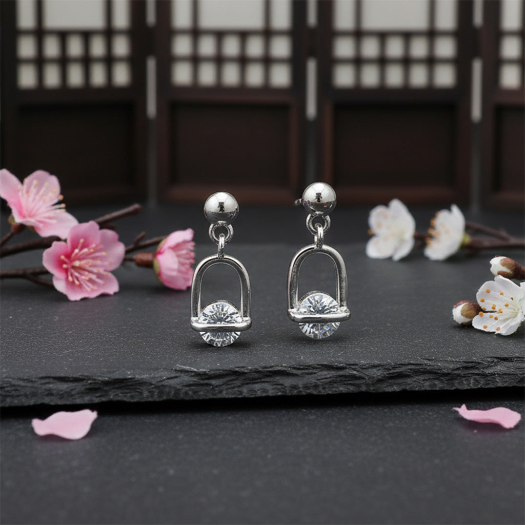 Silver earrings with floral decorations on a dark surface