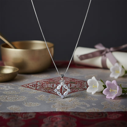 Silver necklace with a diamond pendant on a patterned surface with flowers and bowls.