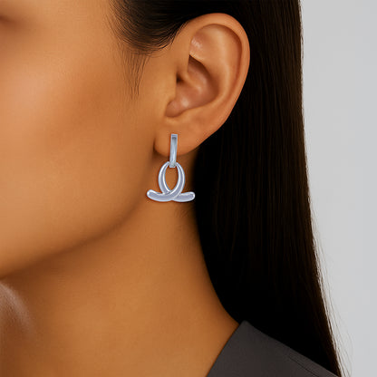 Silver hoop earrings worn by a person with a neutral background