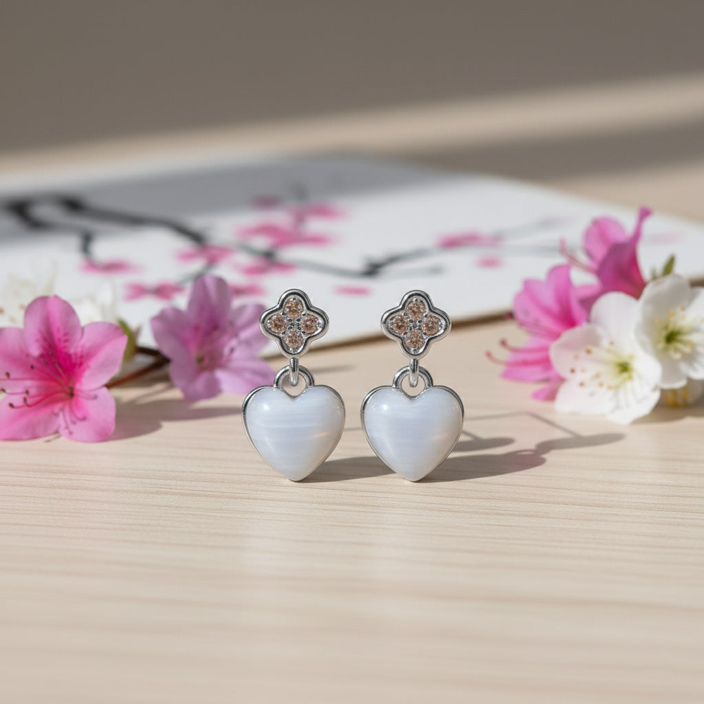 Heart-shaped earrings with floral design on a wooden surface with flowers in the background
