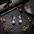 Pearl earrings on a dark surface with flowers and a tea cup in the background