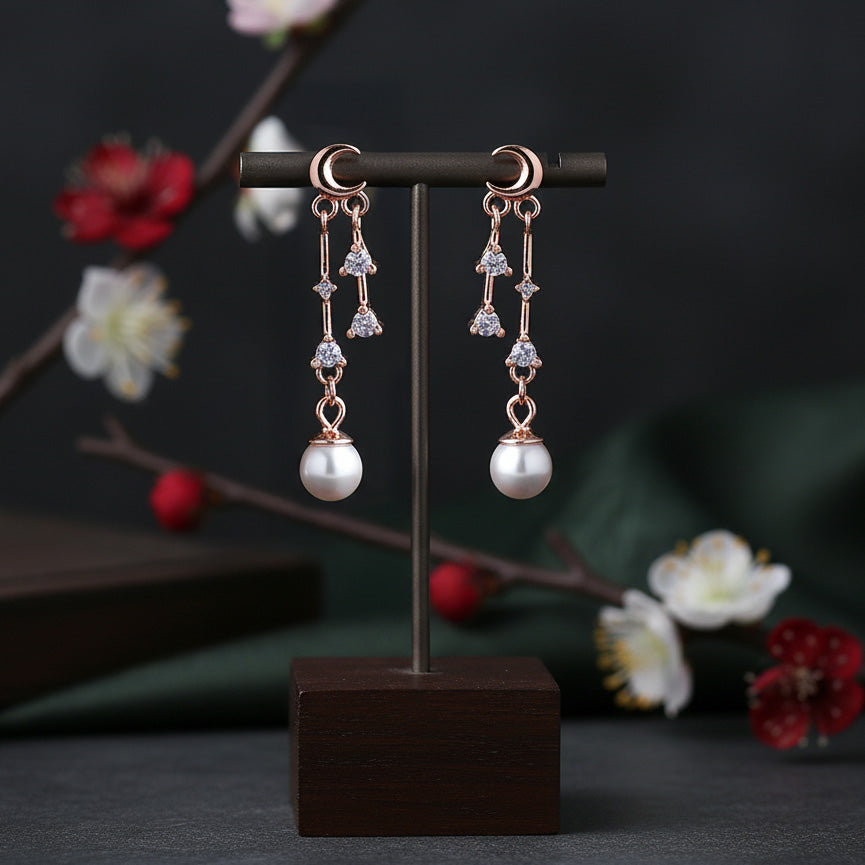 Pair of pearl earrings on a dark stand with a floral background