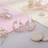 Rose gold hoop earrings with white stones on a soft pastel background