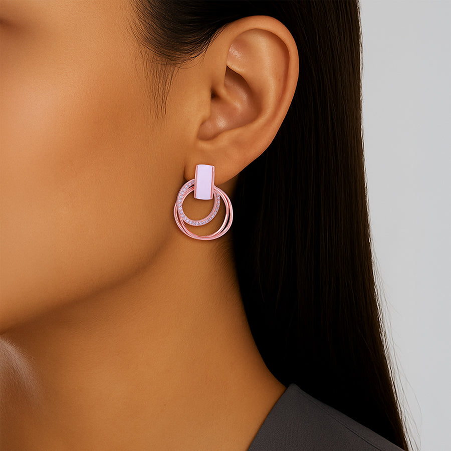 Close-up of a person wearing pink hoop earrings with a neutral background