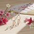 Rose gold earrings with clear stones on a wooden surface with cherry blossoms