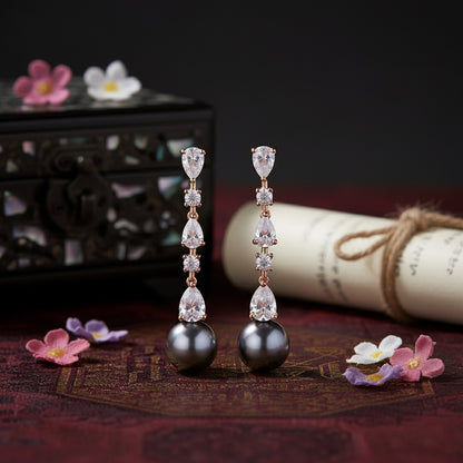 Pair of earrings with black beads and clear gemstones on a dark background with decorative elements.