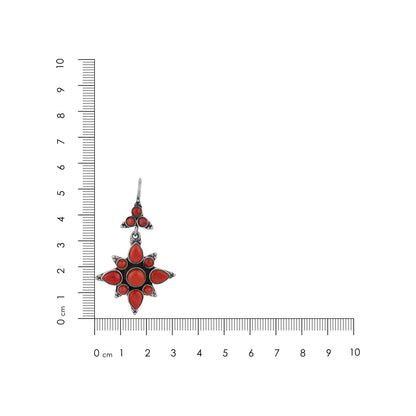Red star-shaped earring with silver accents next to a ruler on a white background
