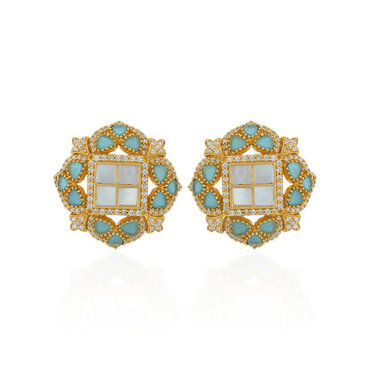 Pair of ornate earrings with gold frame, turquoise stones, and white center on a white background
