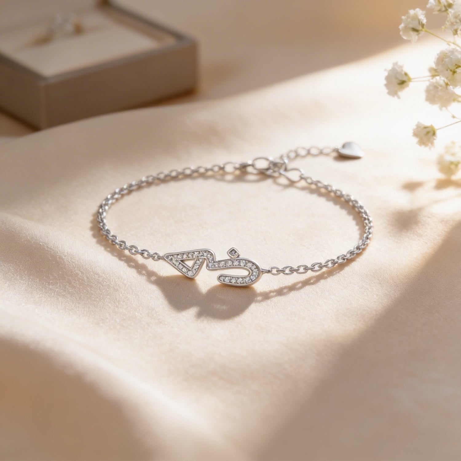 Silver bracelet with a decorative clasp on a soft beige surface with flowers.