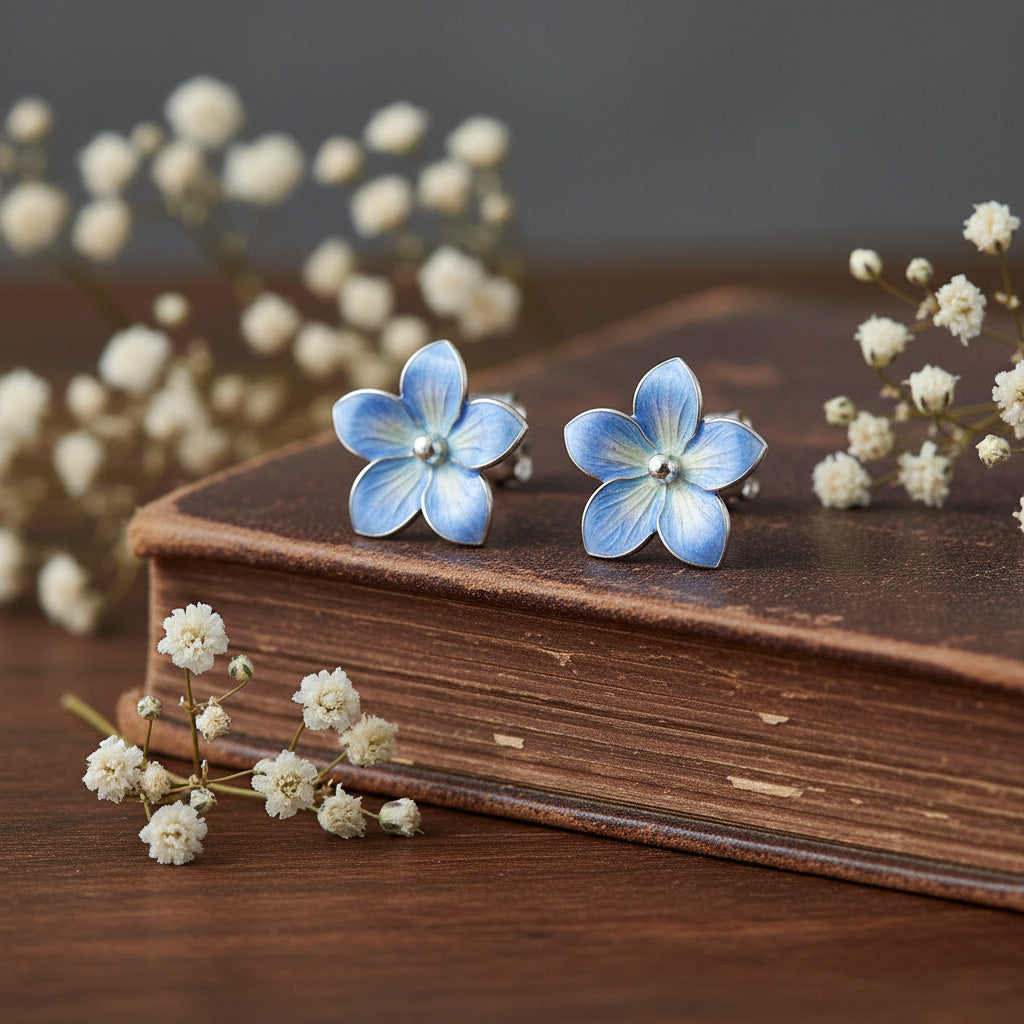 Blue flower-shaped earrings on a wooden surface with white flowers.