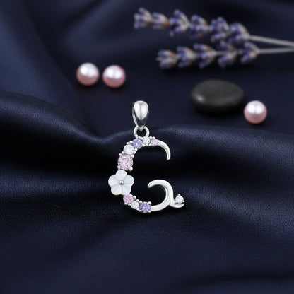 Silver pendant with floral design on a dark fabric background