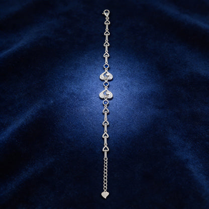 Silver bracelet with heart-shaped charms on a dark blue fabric background