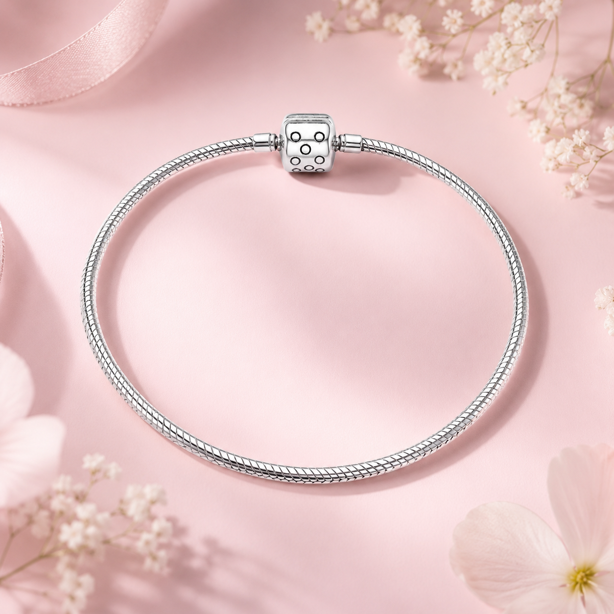 Silver bracelet with a matching charm on a pink background with flowers