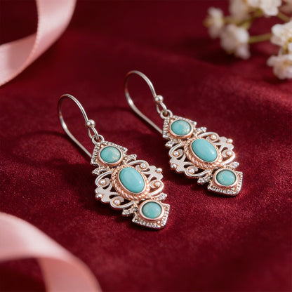 Ornate earrings with turquoise stones on a red fabric background