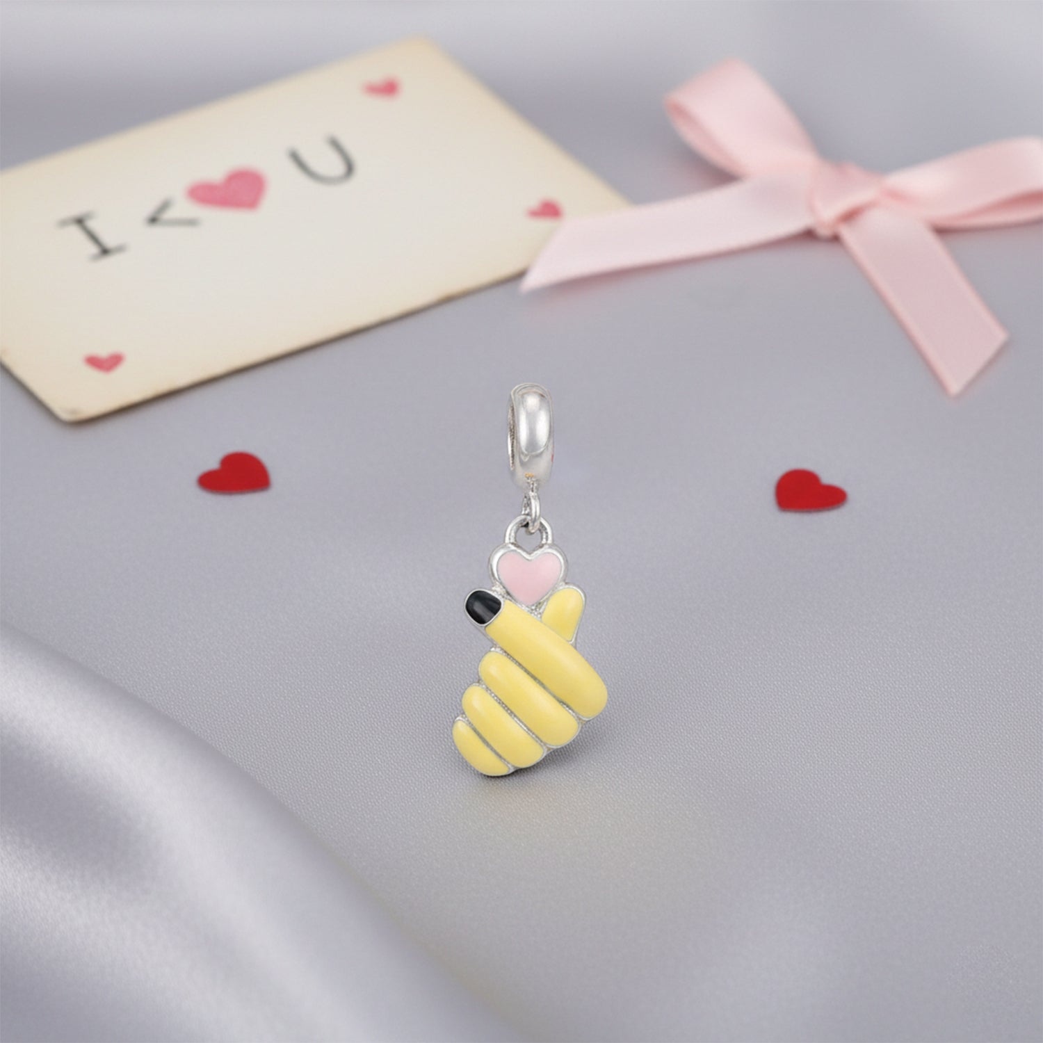 Yellow bee-shaped charm with a pink heart on a gray surface with &