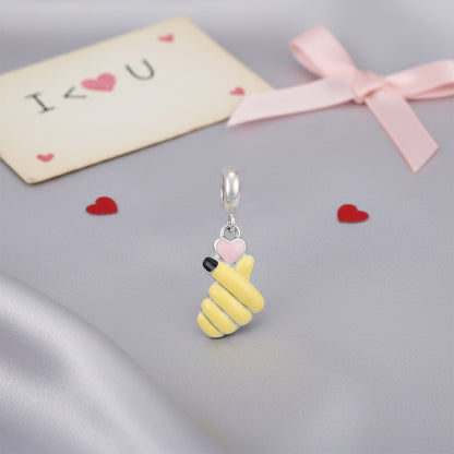 Yellow bee-shaped charm with a pink heart on a gray surface with &
