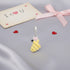Yellow bee-shaped charm with a pink heart on a gray surface with &