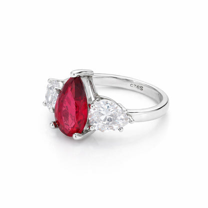 Silver ring with a red gemstone and clear stones on a white background