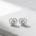 Pair of silver earrings with circular design on a light gray background