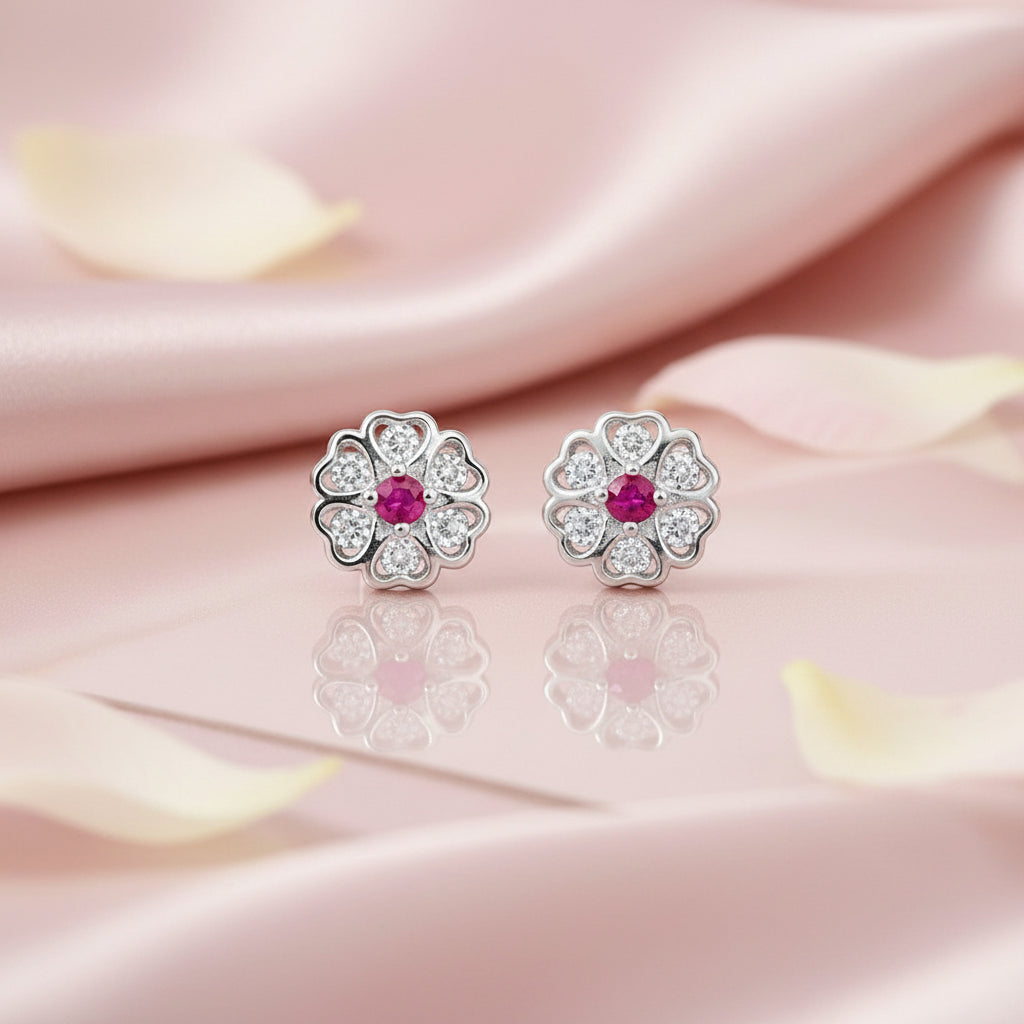 Flower-shaped earrings with red gemstones on a pink satin background