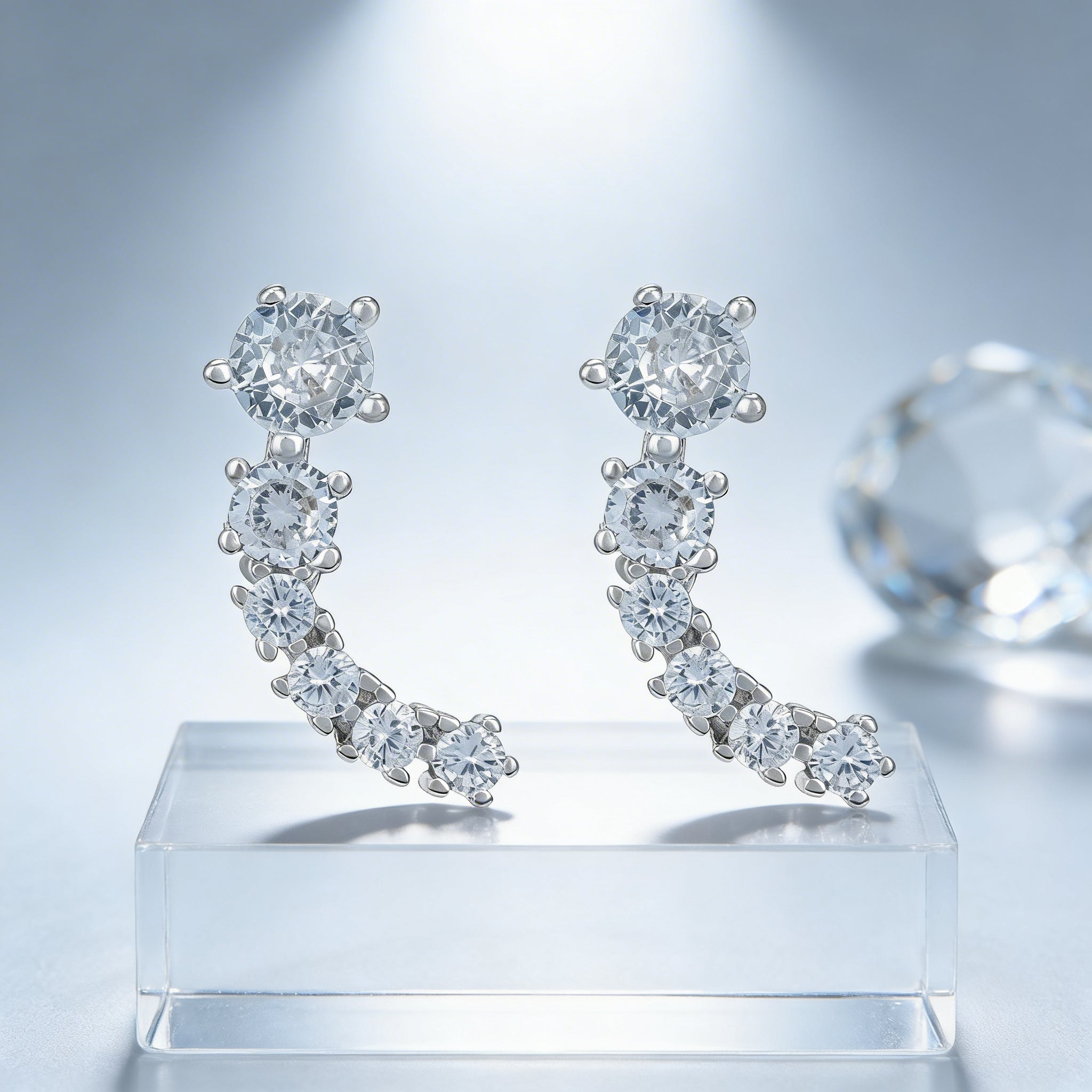 Diamond earrings on a clear stand with a light gray background