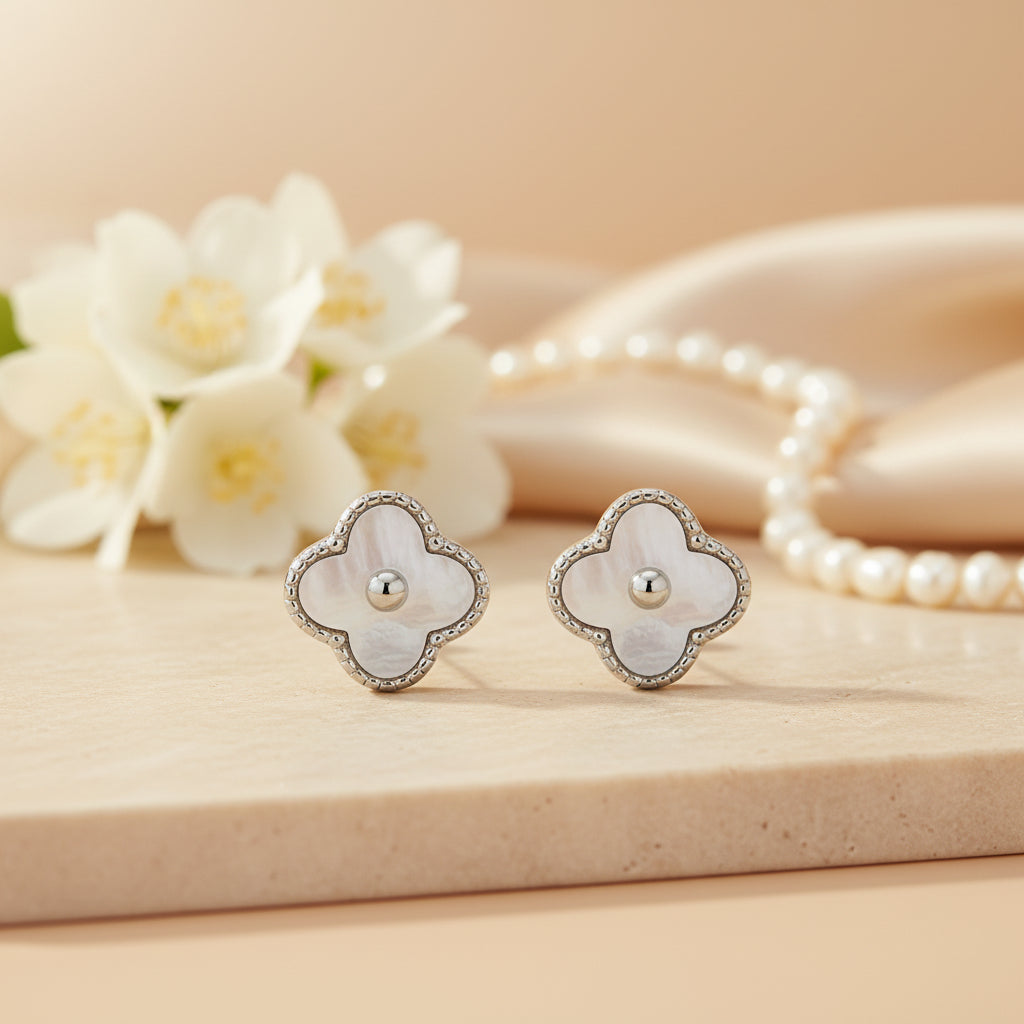 Flower-shaped earrings on a beige surface with flowers and pearls in the background