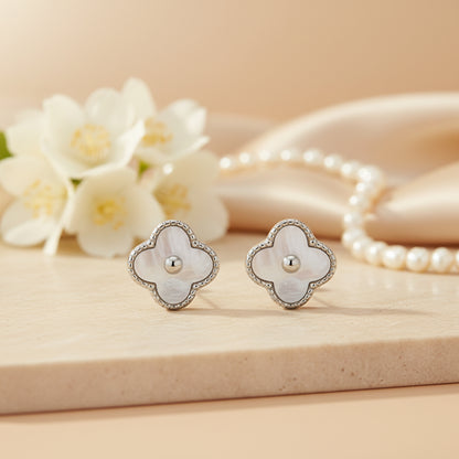Flower-shaped earrings on a beige surface with flowers and pearls in the background