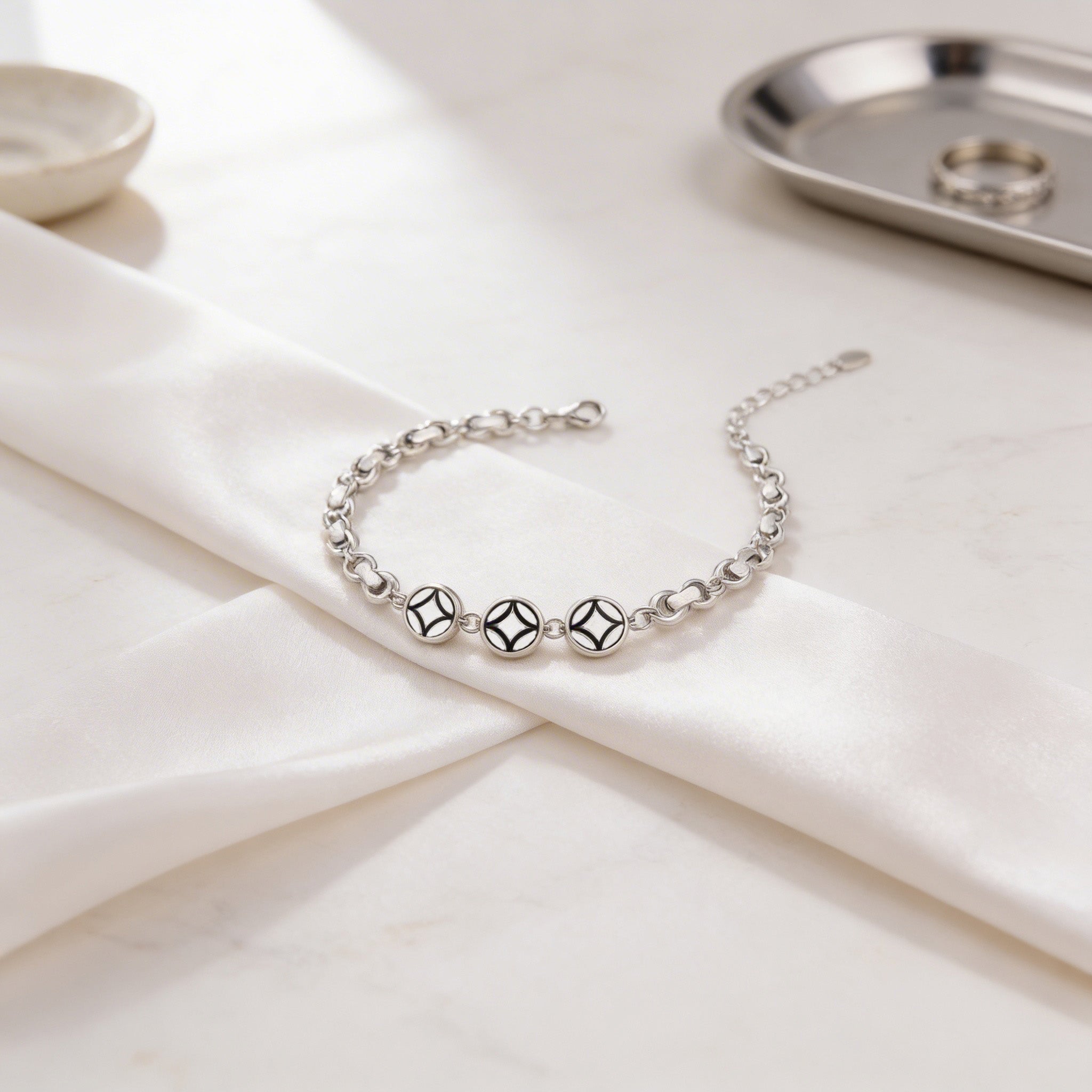 Silver bracelet on a white fabric surface with a neutral background